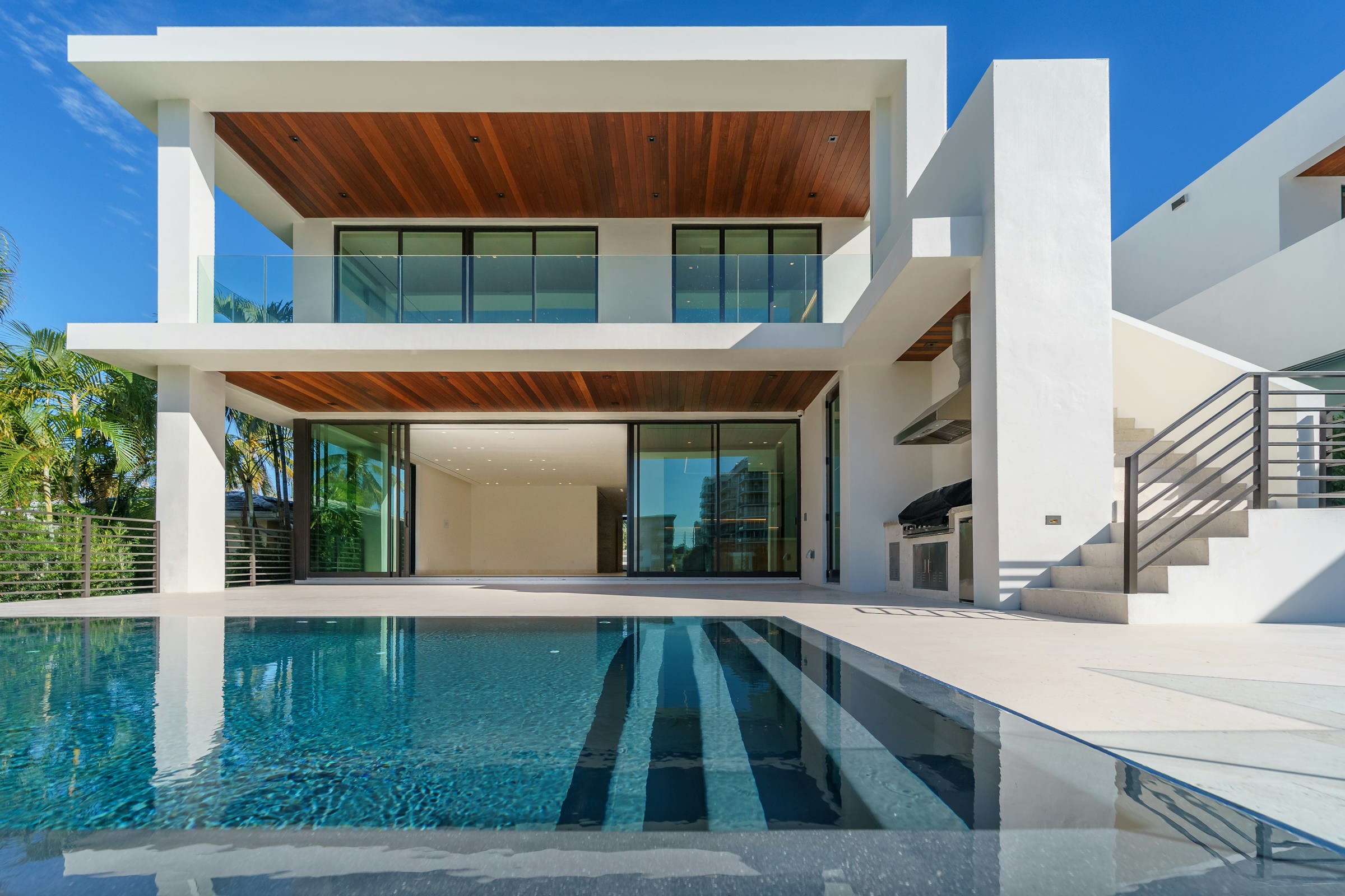 White modernist house with cedar-lined soffits overlooking a long reflecting pool