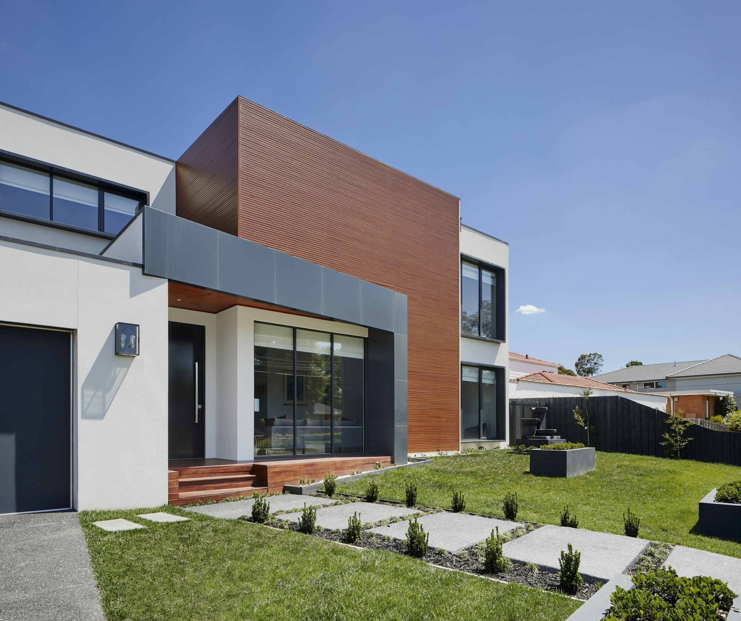 Contemporary home with a copper-toned cladding volume and stepping-stone garden path